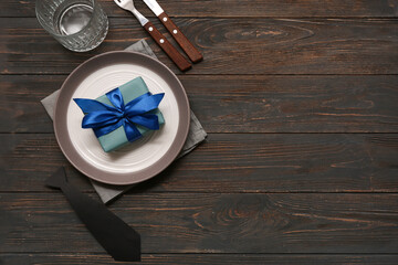 Beautiful table setting with gift box on black wooden background. Father day celebration concept