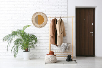 Stylish interior of modern hall and rack with autumn clothes