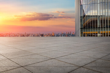 Empty square floor and glass wall building with city skyline at sunrise in Shanghai