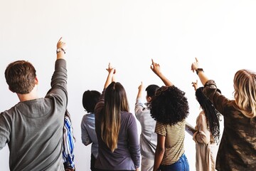 Group of diverse people pointing at a blank wall. Mixed genders, ethnicities, and ages. Diverse group engaged and presenting. People presenting together at a wall.