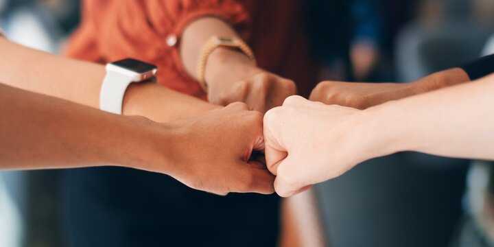 Diverse group of business people teamwork fist bumping. Diverse hands from business team fist bumping in unity. Teamwork and unity among diverse business people. Close-up of diverse hands fist bump