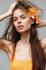 Young woman with long hair and orange flower, expressing confidence in a vibrant orange outfit...