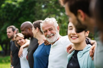 Elderly man and diverse people hugging each other. Diverse group of women and men embrace each...