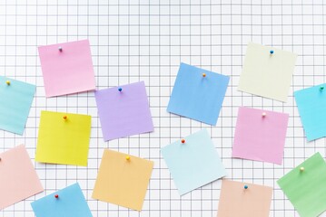 Colorful sticky notes on a grid background. Sticky notes in pink, blue, yellow, and green. Grid...