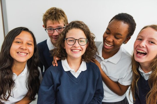 Group of diverse students smiling in school uniforms. Happy students, diverse backgrounds, school setting. Smiling faces, diverse group, school uniforms. Diverse international high school students.