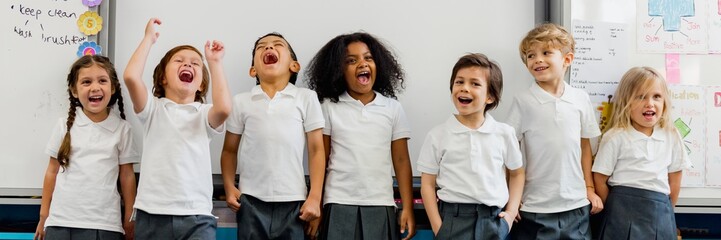 Group of diverse children in school uniforms laughing and smiling in a classroom. Happy kids in uniforms enjoying school. Diverse classroom with children. Diverse elementary school children in uniform