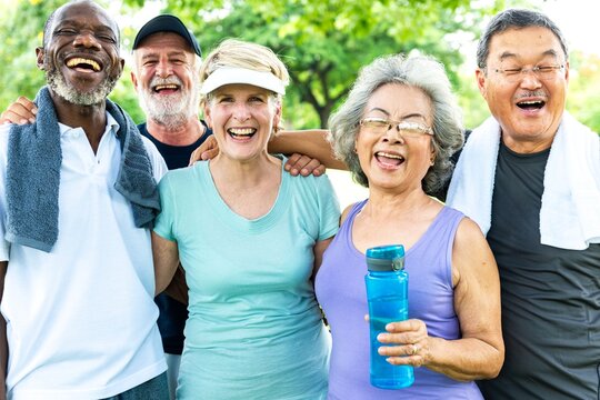 Group of diverse seniors smile after exercise in park. Happy diverse seniors group enjoy outdoor exercise. Senior friends group smile happily in park. Happy diverse senior friends exercise outdoors