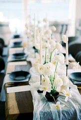 White bouquets of flowers stand on a festive table next to black plates