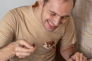 Young man eats cake and smiles happily. Close-up, headshot