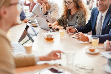 Group of business people in a meeting, discussing ideas. Laptops and coffee cups on the table. Collaborative work environment with diverse team members. Business people working at a cafe, remotely.