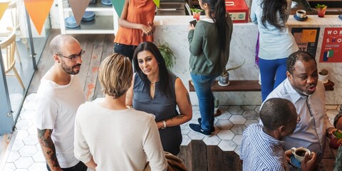 Diverse group socializing in a cafe. Diverse people chatting, enjoying drinks. Casual, friendly atmosphere. Cafe setting with diverse individuals, lively conversation. Coffee shop with people talking