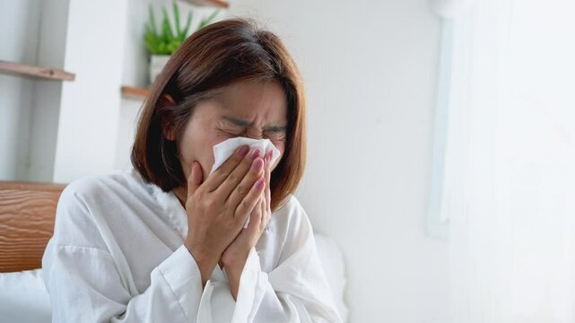 asian woman coughing, sneezing, and have runny nose due to a cold, flu, or allergies, feeling uncomfortable from dust, pollen, and pm2.5 air pollution, difficulty to breathe 