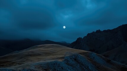 Under a clear night sky, a full moon illuminates the rocky terrain, revealing the rugged contours of the mountains and valleys. The cool atmosphere evokes tranquility at dusk