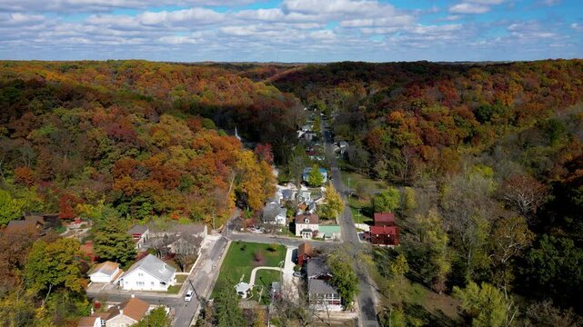 A shot pulling up and back showing the small town of Elsa, Illinois during autumn. The sun is shining and the colors on the trees are especially vibrant.
