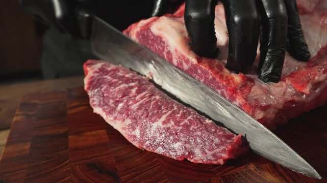 They are cutting raw meat on a wooden cutting board.
