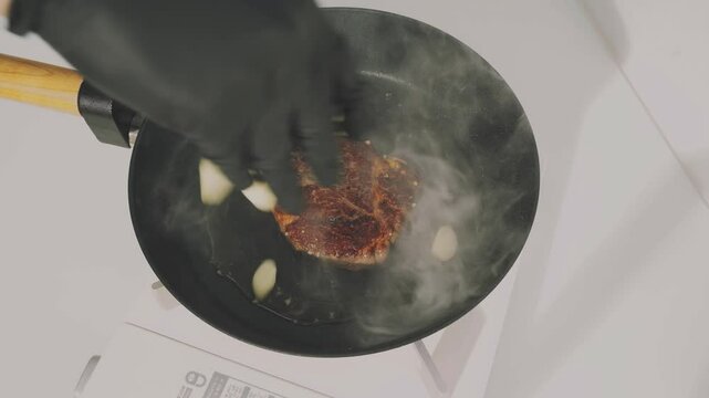 Grilling steak, garlic and tomatoes in a pan.