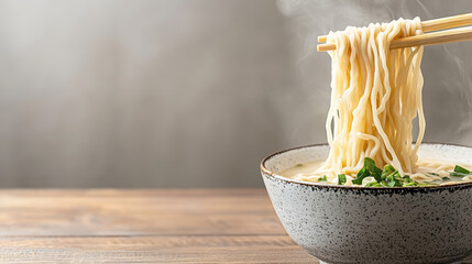 close up of chopsticks lifting silky ramen noodles from bowl, evoking warmth and comfort