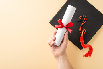 Close-up of a diploma held by a hand, with a graduation cap and tassel nearby