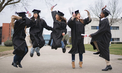 Happy group of diverse graduated students jumping with diplomas outdoors in the university campus