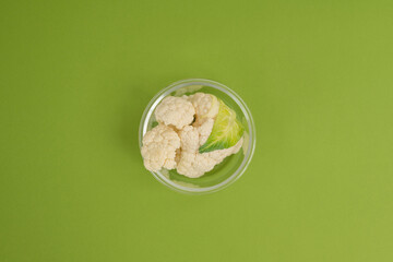 A bowl of fresh cauliflower on a green background