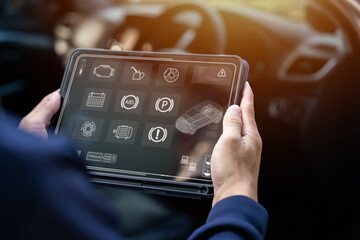Auto mechanics use tablet computers with cutting-edge interactive diagnostic software to find faulty parts in the engine compartment.