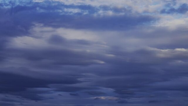 Scenic time-lapse footage of the dense white clouds rolling in the dusk sky in the evening
