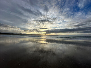 Evening sunset colors reflected in a receding wave on a beach