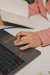 Fototapeta premium Cropped image of professional businesswoman working at her office via laptop, young female manager using portable computer device while sitting at modern loft, flare light, work process concept