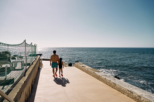 father and daughter holding hands on the ocean beach
