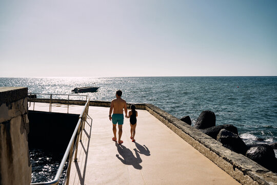 father and daughter holding hands on the ocean beach