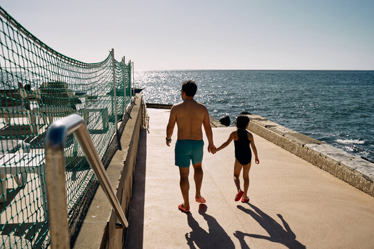 father and daughter holding hands on the ocean beach