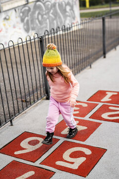Toddler girl playing at an outdoor playground, jumping