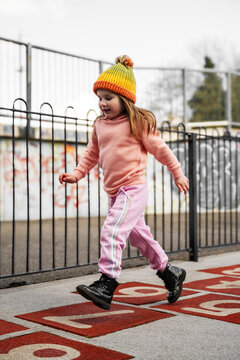 Toddler girl playing at an outdoor playground, jumping
