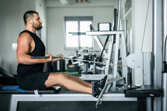 Athletic man training on a cable row machine in a modern gym