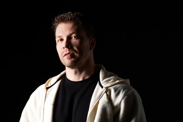 Serious man in white fleece jacket, dramatic lighting.