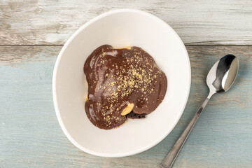 Delicious profiteroles with chocolate sauce on a white porcelain plate