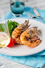 Red prawns or tiger prawns on a white plate with greens and tomatoes. Tiger shrimps