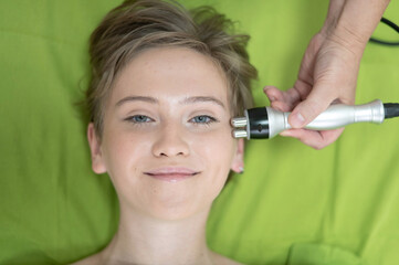 Top view of Caucasian woman undergoing radio wave RF lifting procedure in beauty salon. 