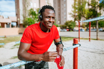 Sportsman drinking isotonic drink and listening music