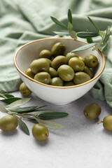 Fresh green olives with olive branches in a bowl, displaying mediterranean flavors