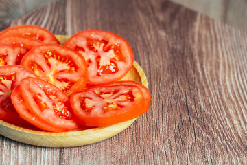 Sliced Red Tomatoes on a Plate with Wooden Background