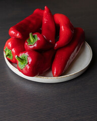  bunch of fresh red bell peppers on white dish dark background close-up