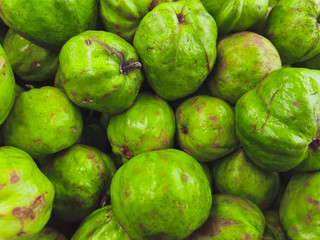 Close-up of a pile of bright green guavas, a tropical fruit known for its sweet, slightly acidic flavor and numerous health benefits