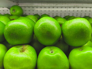 Close-up of fresh, green apples stacked neatly in a display