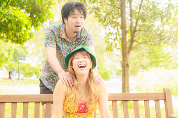 Fototapeta premium ベンチに座る彼女を後ろから抱きしめる彼氏