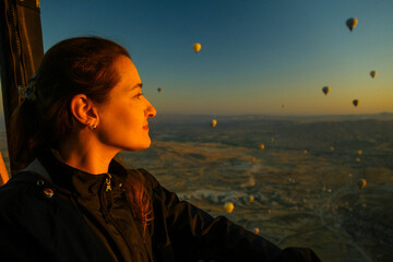 Woman contemplating the beauty of a sky full of balloons in Cappadocia