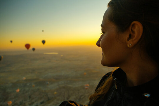 White woman looking down from a hot air balloon in Cappadocia