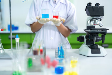 Fototapeta premium Research and experiments using glass tubes filled with chemicals to produce vaccines in the lab by an Asian female scientist for the future of medicine to treat patients' diseases.