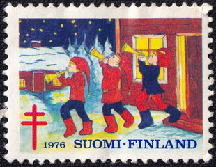 Finnish postage stamp from 1976 depicting children in traditional Christmas attire playing trumpets...