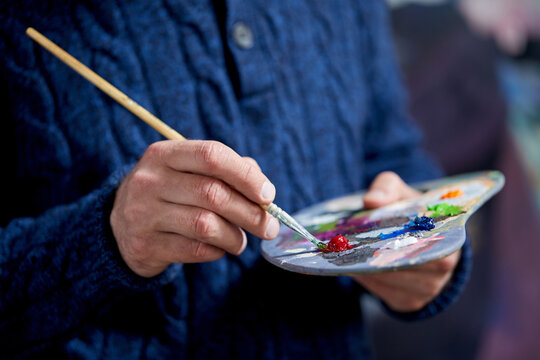 the artist holds a palette with paints and a brush and is going to paint on canvas